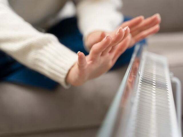 close-up-hands-warming-up-near-heater_23-2149335074